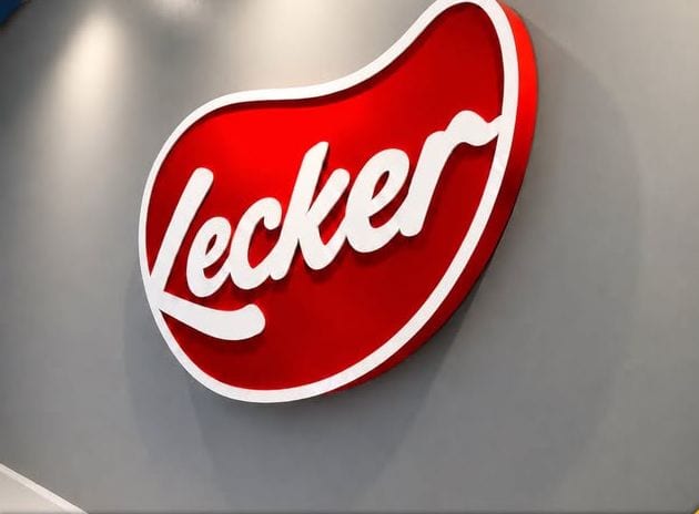 A red Lecker script logo built as a three-dimensional installation on a plain light wall, shot at an angle that shows the depth of the return.